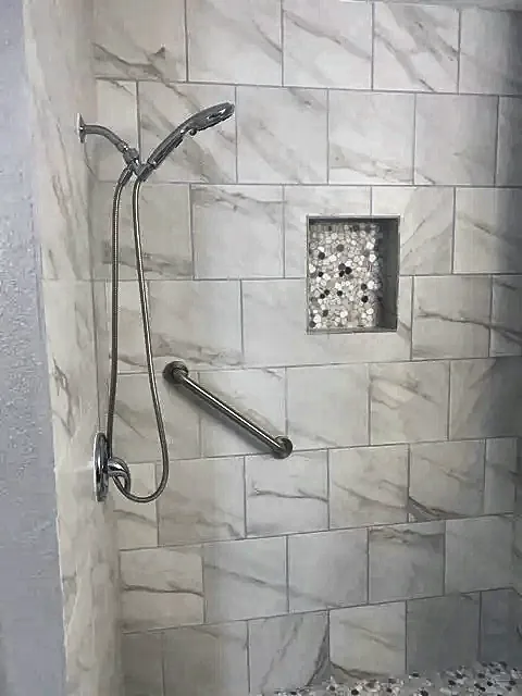 Tile shower with handheld shower head and grab bar by Brown Sterling Builders
