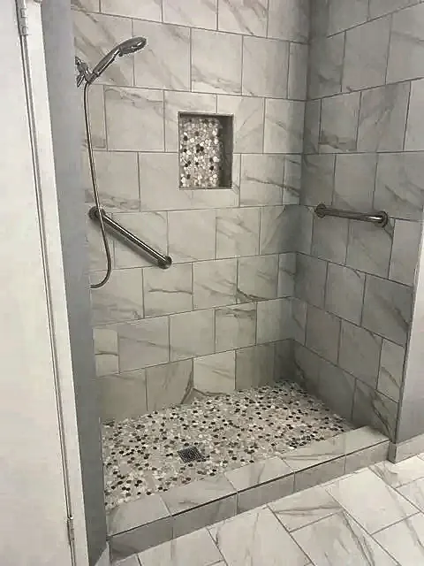 Walk-in tile shower with pebble floor, niche and grab bar by Brown Sterling Builders