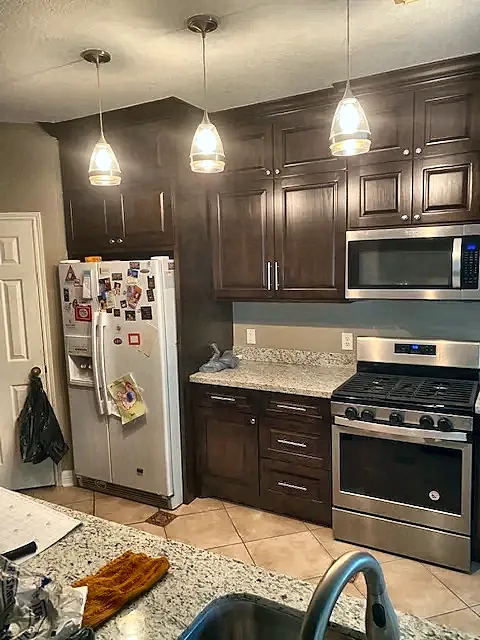 Kitchen with dark cabinets, pendant lights and stainless appliances by Brown Sterling Builders